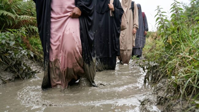 A group of Muslim women wade through muddy water during their Trials & Tribulations challenge.