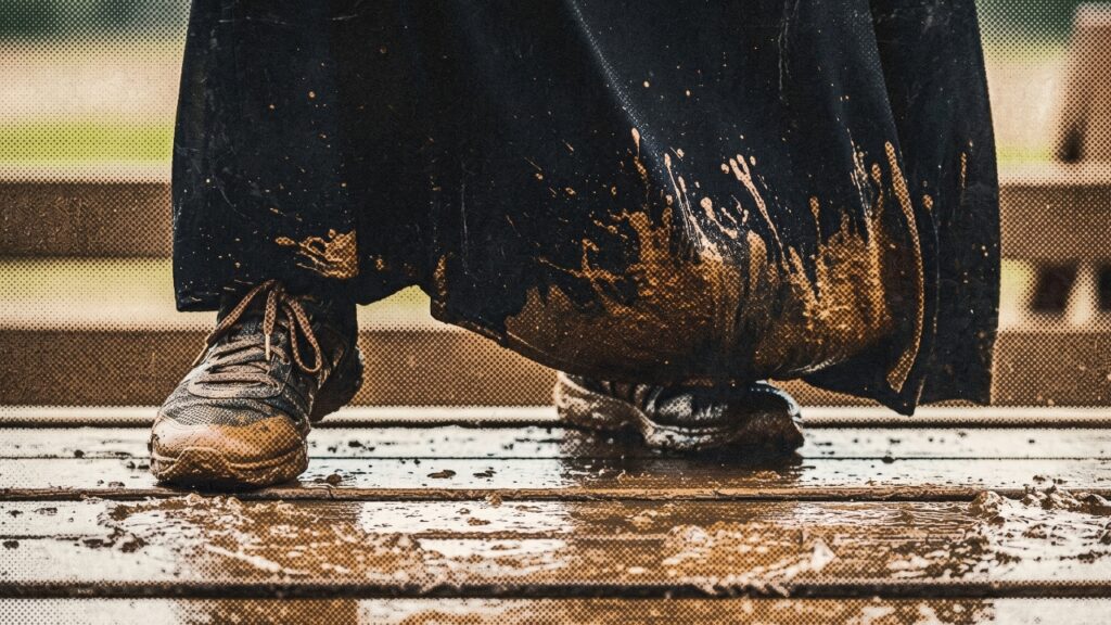 A Muslim woman stands on a muddy wooden platform during her Trials & Tribulations challenge.