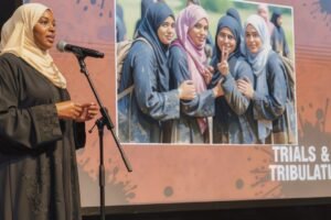 Painting depicting a Muslim woman delivering a presentation in front of an audidence